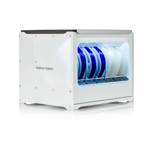 Ultimaker Material Station – sustav s plavim i bijelim filamentima Ultimaker Material Station s transparentnim prozorom, prikazuje organizirane filamentne role u različitim bojama