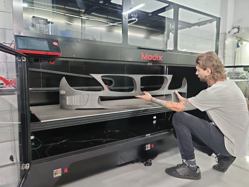 Modix 180X – vađenje gotovog 3D modela iz printera Korisnik uklanja isprintani model iz Modix 180X 3D printera velikog formata